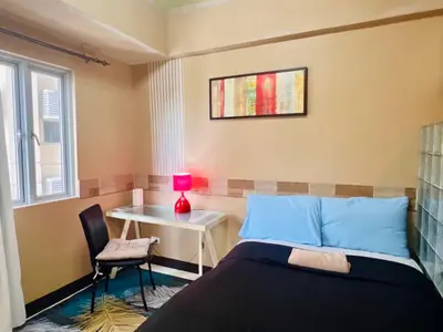 a bedroom with a bed and a table and a lamp at Heart of BGC in Manila