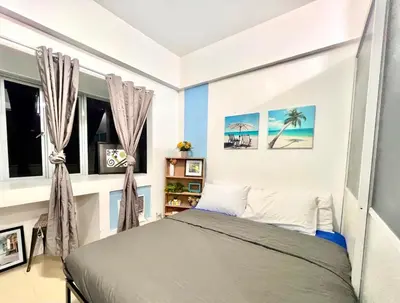 a bedroom with a bed and two windows at Cozy Home in BGC in Manila