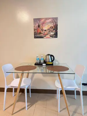 a dining room table with two white chairs and a painting at Condotel near NAIA T3 Airport in Manila