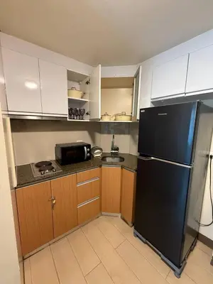 a kitchen with a black refrigerator and wooden cabinets at Condotel near NAIA T3 Airport in Manila