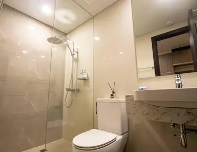 a bathroom with a shower and a toilet and a sink at The Room of Requirement in Manila