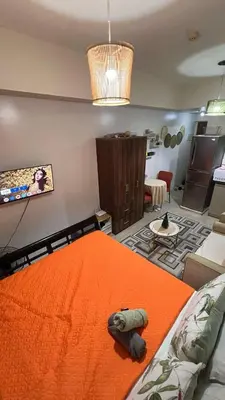 a bedroom with an orange bed and a living room at Sophia's Place Beacon Amorsolo in Manila