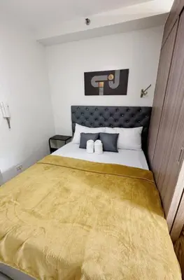 a bedroom with a large bed with a yellow blanket at 19106 Condotel at Shore 2 MOA wNetflix in Manila