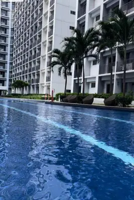 a large blue swimming pool in front of a building at 19106 Condotel at Shore 2 MOA wNetflix in Manila