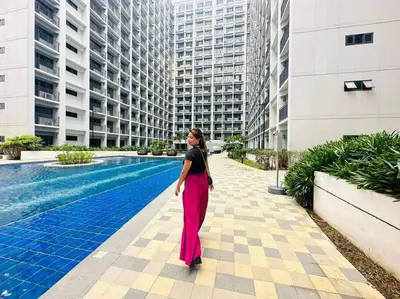 a woman is standing in front of a building at 19106 Condotel at Shore 2 MOA wNetflix in Manila