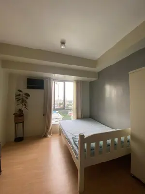 a bedroom with a bed and a window at Condo near ATC- Molito Alabang, Muntinlupa in Manila