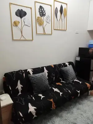 a black couch in a living room with four pictures on the wall at Spring Residences 2BR R&D Staycation and Condotel in Manila