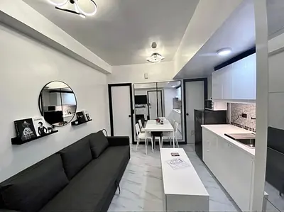 a living room with a black couch and a kitchen at Chic and Cozy Minimalist Condo with Pool in Makati City in Manila