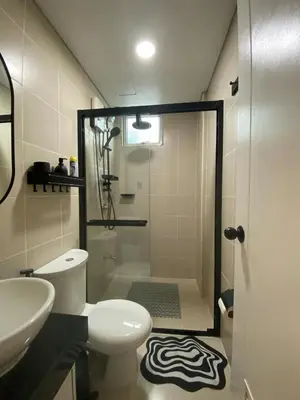 a bathroom with a shower and a toilet and a sink at Chic and Cozy Minimalist Condo with Pool in Makati City in Manila