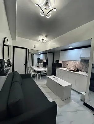a living room with a couch and a kitchen at Chic and Cozy Minimalist Condo with Pool in Makati City in Manila