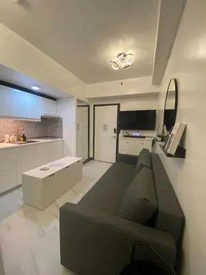a living room with a couch and a kitchen at Chic and Cozy Minimalist Condo with Pool in Makati City in Manila