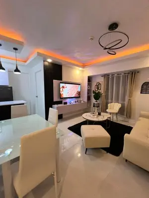 a living room with a glass table and white chairs at Lucky 7 Suites in Manila