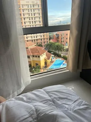 a bed in front of a window with a view of a pool at LUCKY 7 Suites in Manila
