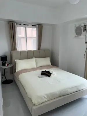 a white bedroom with a bed with a book on it at LUCKY 7 Suites in Manila