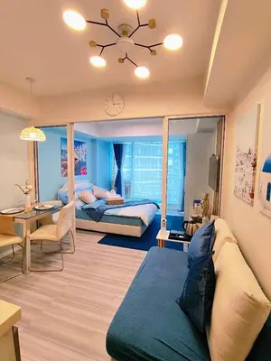 a bedroom with a bed and a couch and a table at Oveecation Suites St Tropez Tower in Manila