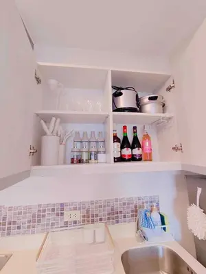 a kitchen with a sink and a shelf with bottles at Oveecation Suites St Tropez Tower in Manila
