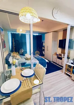 a living room with a dining table and a clock at Oveecation Suites St Tropez Tower in Manila