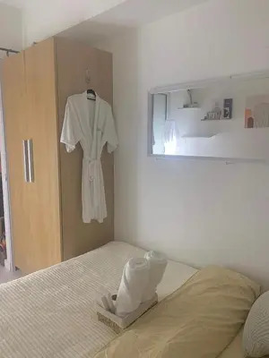 a bedroom with a bed with a robe hanging on a wall at Oveecation Suites Positano Tower in Manila