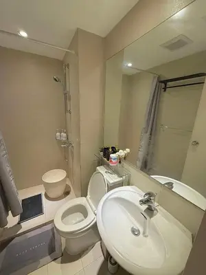 a bathroom with a sink and a toilet and a mirror at Oveecation Suites Positano Tower in Manila