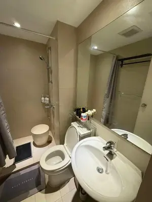 a bathroom with a sink and a toilet and a mirror at Oveecation Suites Positano Tower in Manila