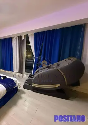 a bedroom with a bed and blue curtains and a couch at Oveecation Suites Positano Smarthome in Manila