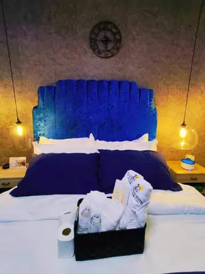 a bed with a blue headboard and a tray of towels at Oveecation Suites Positano Smarthome in Manila