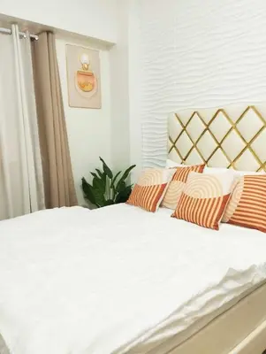 a bed with orange and white pillows on it at Condo in Las Piñas- The Suite Spot Alabang in Manila