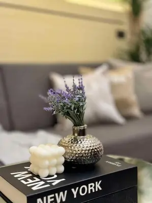 a vase with purple flowers on top of a book at Taguig - Modern Luxe at Grace Residences in Manila
