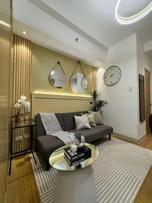 a living room with a couch and a clock on the wall at Taguig - Modern Luxe at Grace Residences in Manila