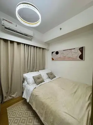 a bedroom with a bed and a chandelier at Taguig - Modern Luxe at Grace Residences in Manila