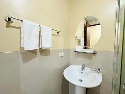 a white bathroom with a sink and a mirror at Makati Beacon Studio Suite in Manila
