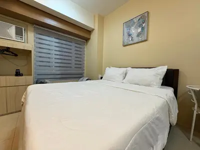a bedroom with a large white bed and a window at Makati Beacon Studio Suite in Manila