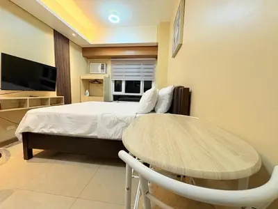 a room with a bed and a table and a tv at Makati Beacon Studio Suite in Manila