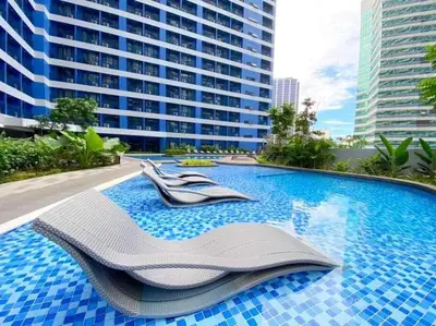 a swimming pool with two chairs and a building at AIR RESIDENCES Makati Netflix plus 200 mbps digital door lock in Manila