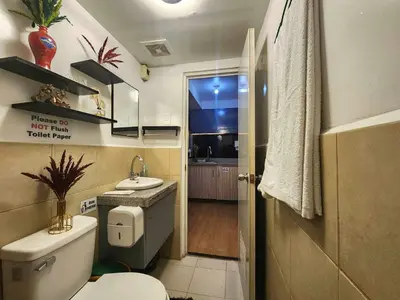 a bathroom with a toilet and a sink and a window at Aura Suites in Imus