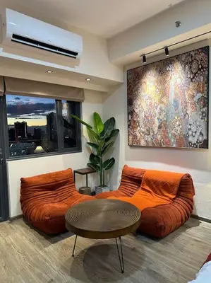 a living room with two orange couches and a table at Prime End Sunset View Unit in Makati in Manila