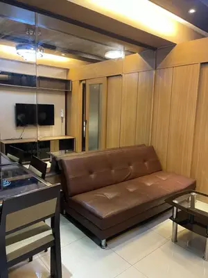 a brown leather couch in a room with a tv at Cozy Staycation by Ayumi in Manila