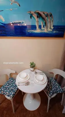 a white table with two chairs and a painting of dolphins at Comfystay at Shore Residences in Manila