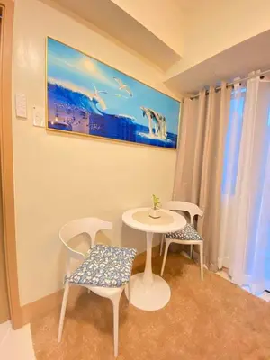 a table and chairs in a room with a painting on the wall at Comfystay at Shore Residences in Manila