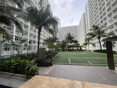 a tennis court in front of a building with palm trees at Shore Family Suite 2 beds for 4 pax TV Netflix WiFi Near MOA NAIA 9116 in Manila