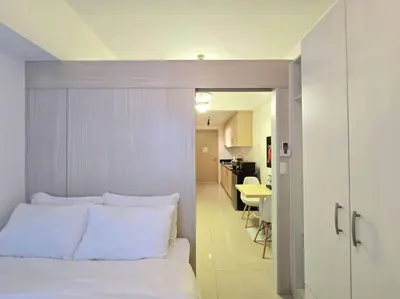 a bedroom with a white bed and a kitchen at 1BR Condotel with Balcony at SM Light Residences #LT11 in Manila