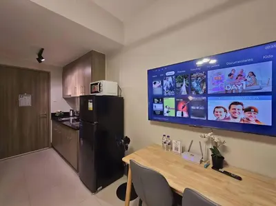 a kitchen with a table and a large screen at 1BR Condotel with Balcony at FAME Residences #FM62 in Manila