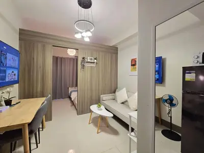 a living room and dining room with a couch and a table at 1BR Condotel with Balcony at FAME Residences #FM62 in Manila