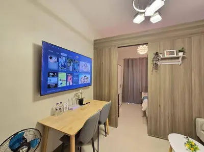a dining room with a table and a tv on the wall at 1BR Condotel with Balcony at FAME Residences #FM62 in Manila