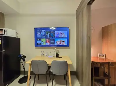 a dining room table with two chairs and a television on the wall at 1BR Condotel with Balcony at FAME Residences #FM62 in Manila