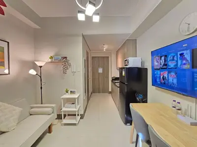 a living room with a couch and a black refrigerator at 1BR Condotel with Balcony at FAME Residences #FM63 in Manila