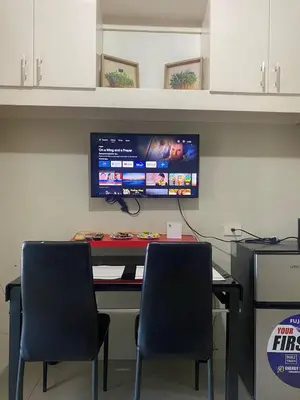 a desk with two chairs and a computer monitor on a wall at P3K Shell Staycation in Manila