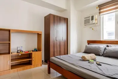 a bedroom with a bed and a wooden cabinet at 2Bedroom 2Bath near moa with Balcony facing pool in Manila