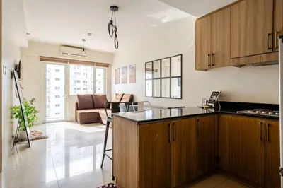a kitchen with wooden cabinets and a living room at 2Bedroom 2Bath near moa with Balcony facing pool in Manila