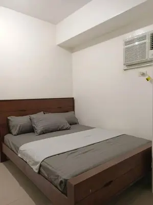 a bed in a bedroom with a white wall at 2Bedroom 2Bath near moa with Balcony facing pool in Manila